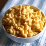 Bowl of creamy macaroni and cheese on a white and blue placemat.