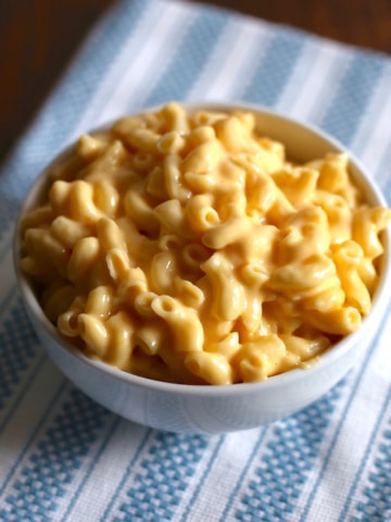 Bowl of creamy macaroni and cheese on a white and blue placemat.
