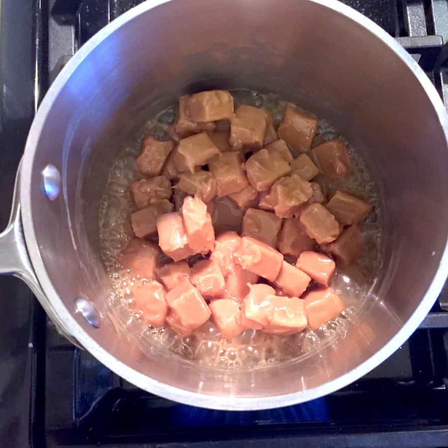 Caramel candies melting in a pot. Bubbles appear on the edge of the pan.