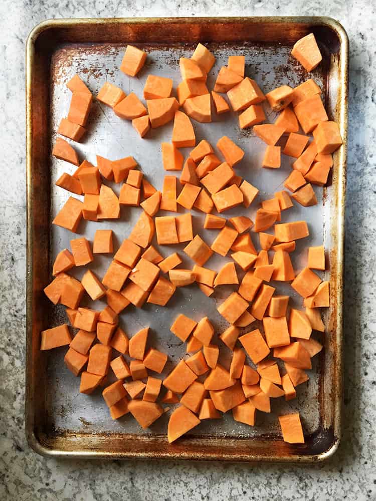 Raw cubes of sweet potatoes on a baking sheet.