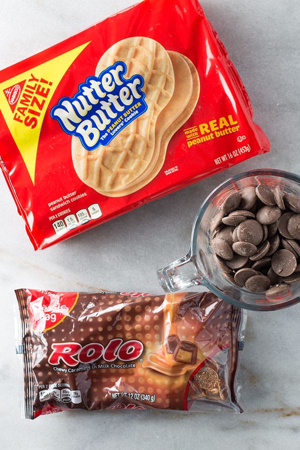 Ingredients needed to make Nutter Butter skateboards. A box of nutter butter cookies. A bag of rolo candies. A measuring cup with chocolate wafers.