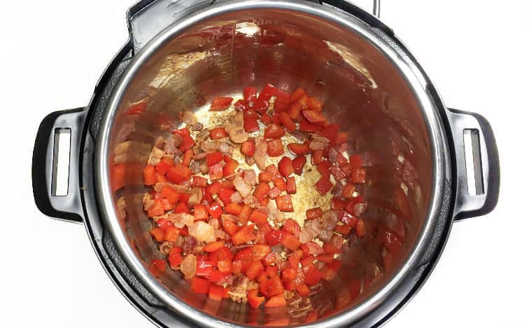 Chopped red bell pepper cooking in a pressure cooker pot.