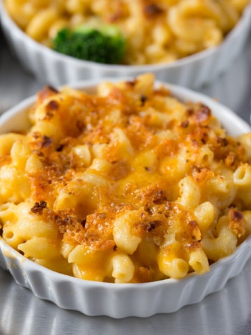 Small bowls of macaroni and cheese topped with melted cheese and breadcrumbs.