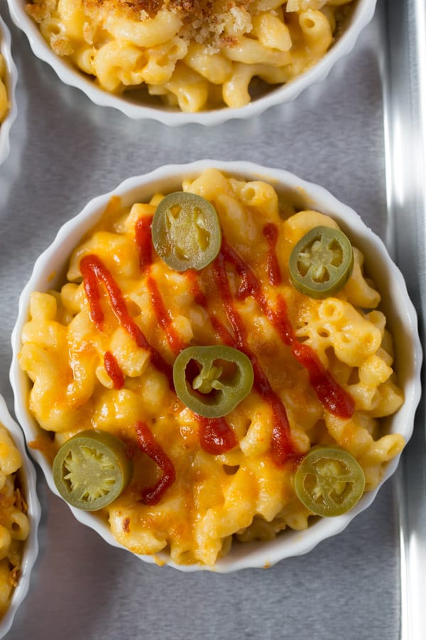 Instant pot mac and cheese in bowl topped with jalapeno and hot sauce.
