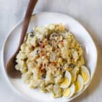 Instant Pot Potato Salad on white plate. Wooden spoon and hard cooked eggs sit alongside.