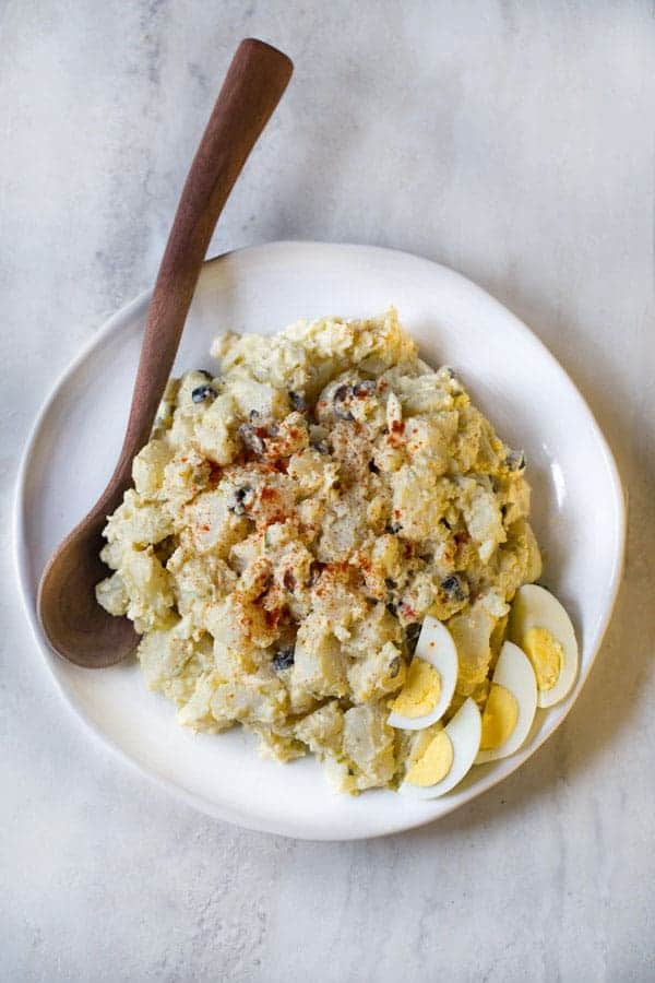 Potato salad with hard cooked eggs on white platter.