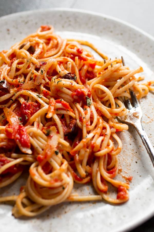 Pasta with tomato sauce and olives on a plate.