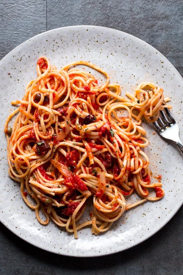 Pasta on a plate with tomato sauce and olives. 