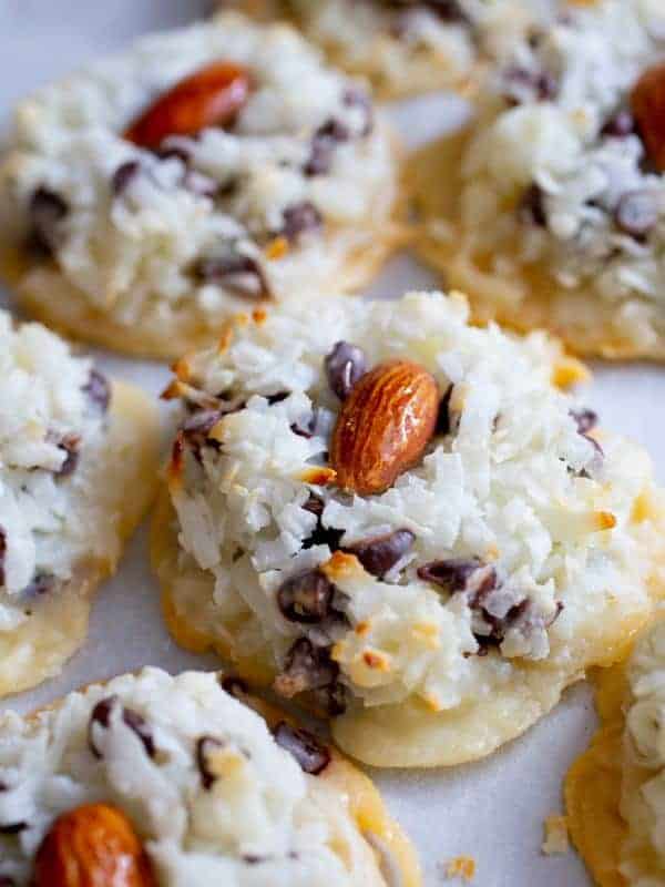 close up of almond macaroon with chocolate chips. Topped with one almond. 