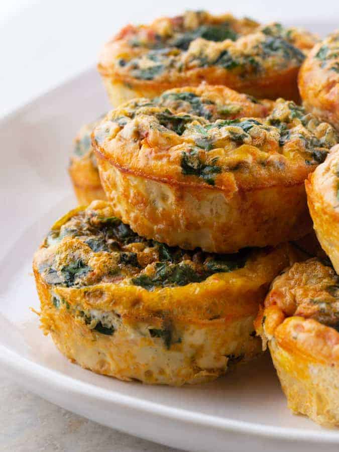 Baked Egg Cups with Spinach Stacked on a Plate.