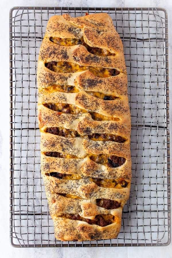 Ground beef and cheese stromboli on wire rack.