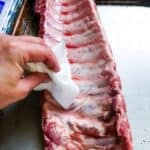 Drying baby back ribs with a paper towel.