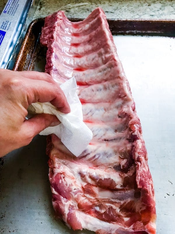 Drying baby back ribs with a paper towel. 