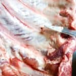 Point of knife under the silverskin of a rack of baby back ribs.