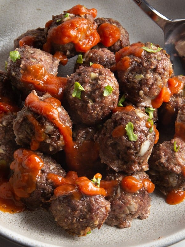 Baked meatballs in a bowl with tomato sauce.