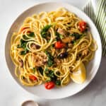 Bowl of Pasta with tuna, spinach, tomatoes, and lemon.