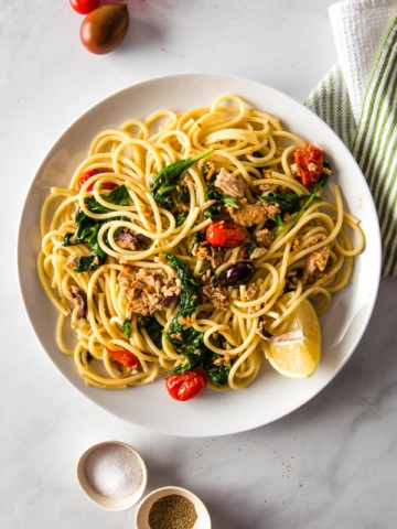 Bowl of Pasta with tuna, spinach, tomatoes, and lemon.