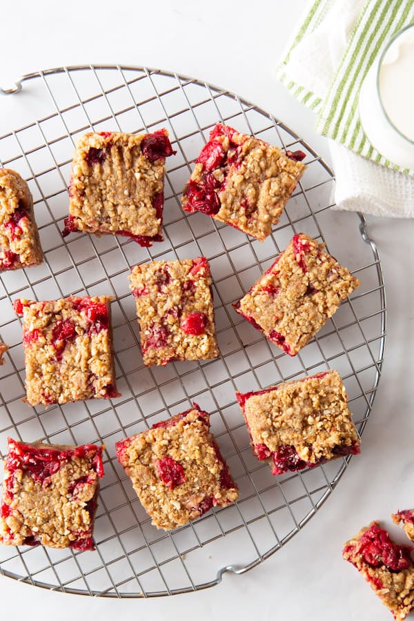 Baked cranberry oatmeal bars on a cooling rack. Glass of milk in upper right corner.