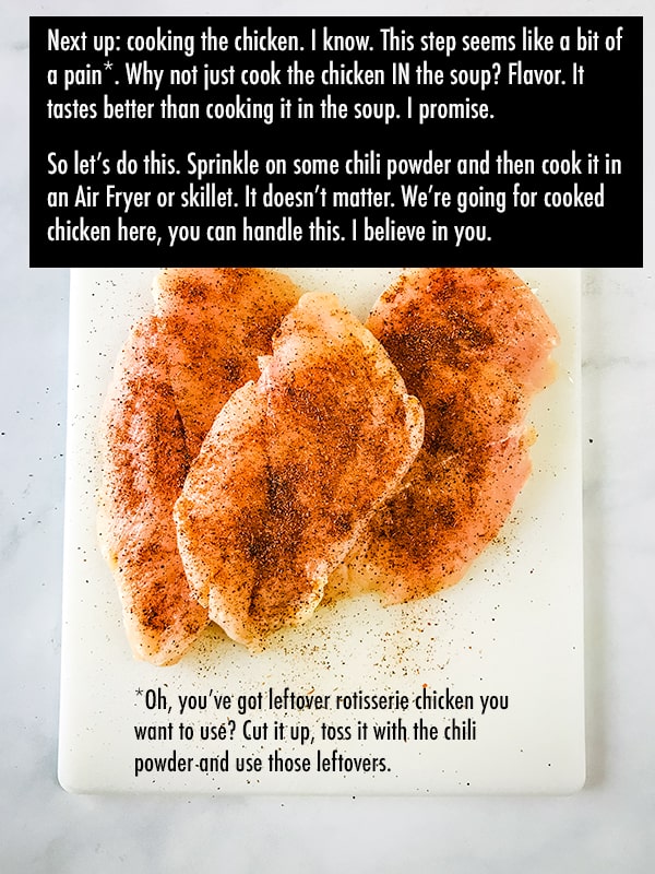 Raw chicken breast sprinkled with seasoning on cutting board.