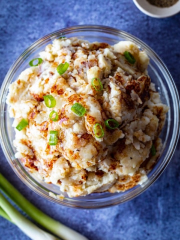 Fried mashed potatoes in a bowl topped with chopped green onions.