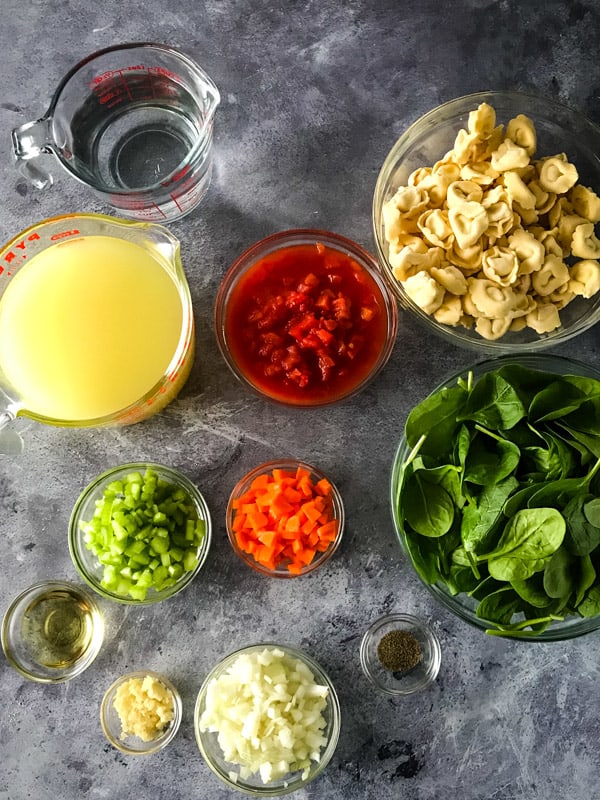 Ingredients for tortellini soup measured and in glass bowls.