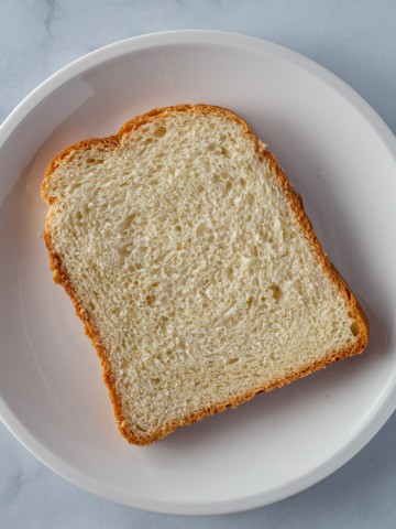 Large slice of sandwich bread on a small white plate.