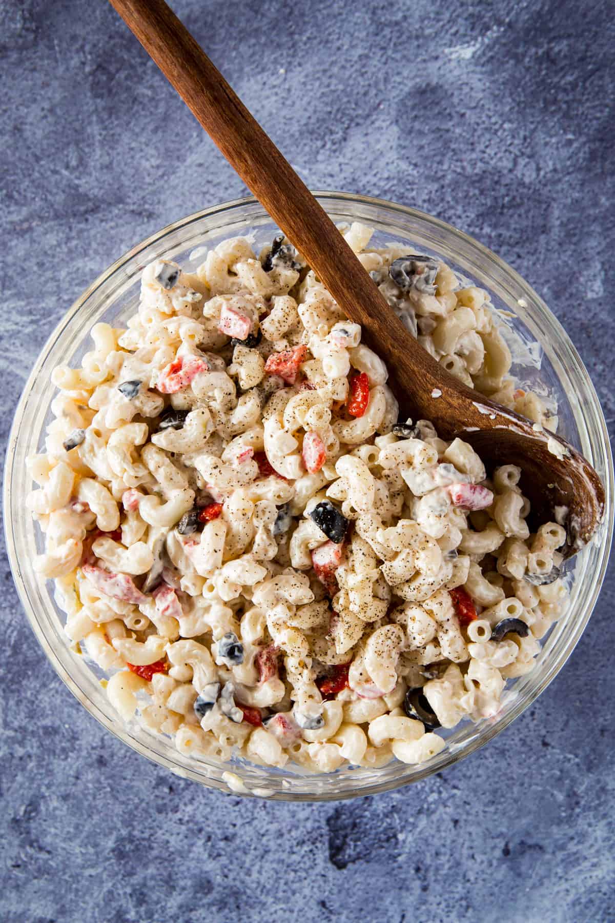 Bowl of macaroni salad with wooden spoon.