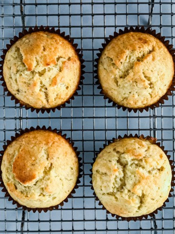Four baked banana muffins on a cooling rack.