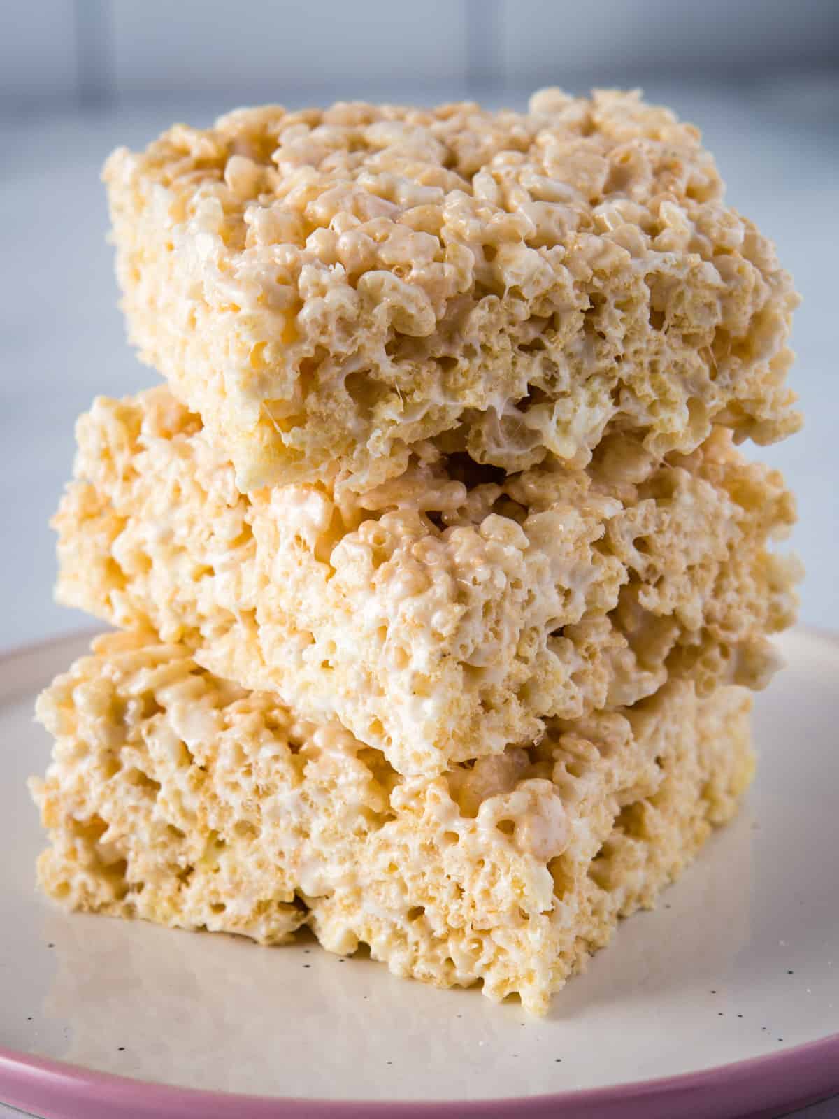 Three rice krispie treats stacked on a plate.