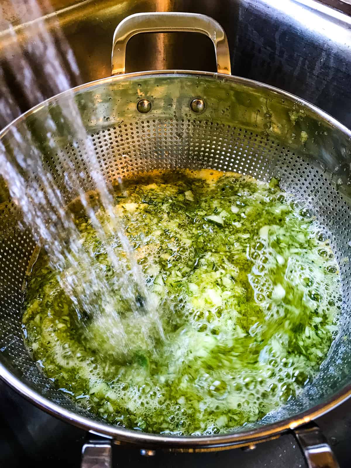 Dill relish being rinsed in a colander.