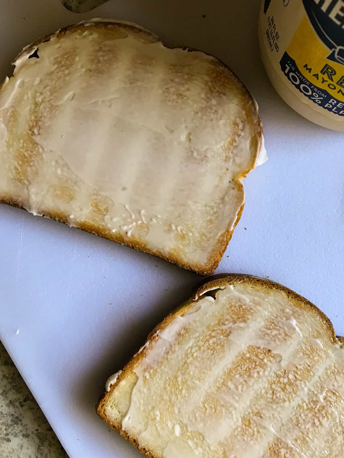 Mayonnaise spread on grilled bread.