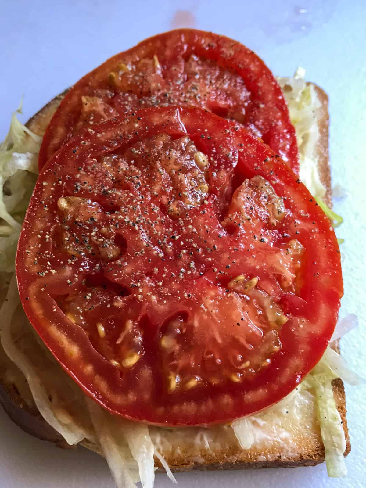 Red tomato with salt and pepper on bread.