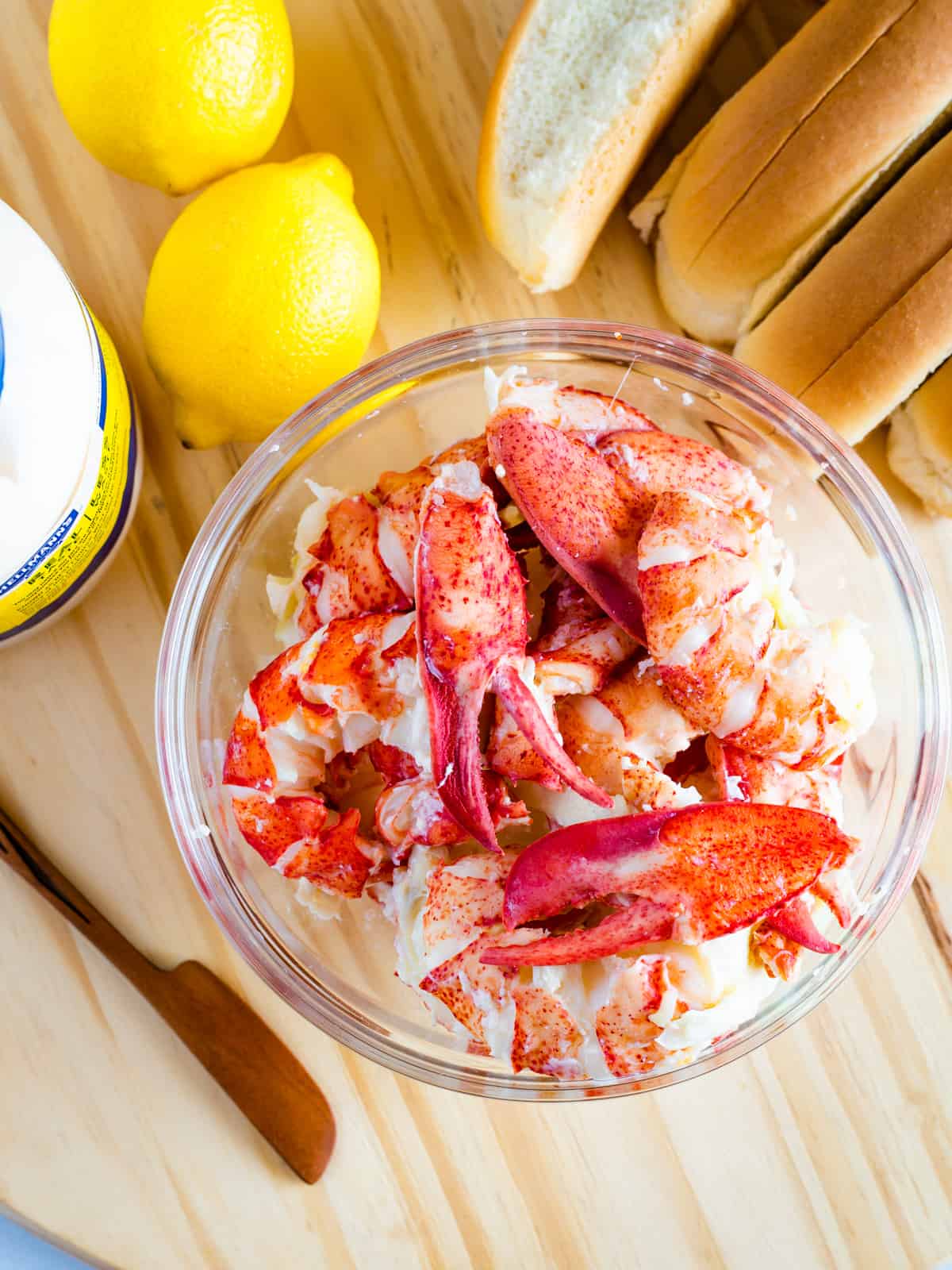 Bowl of lobster meat. Lemons. Hot dog buns and mayo.