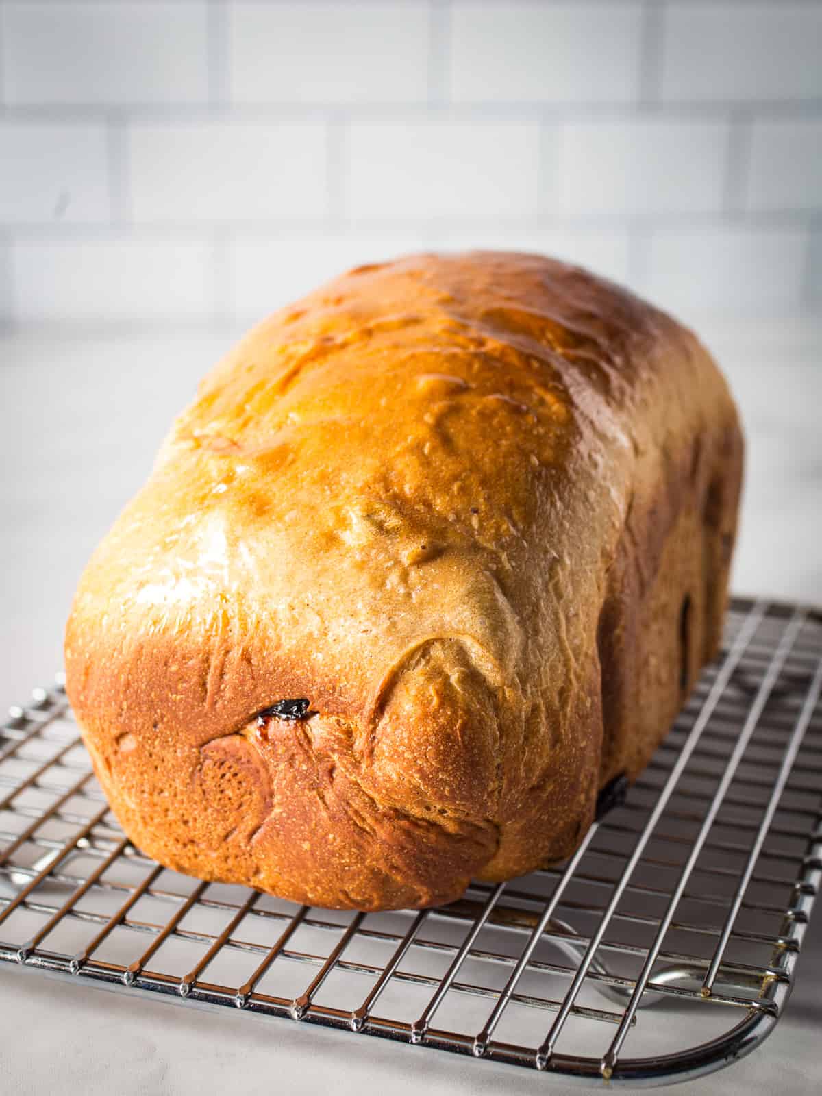 Loaf of cinnamon raisin bread on cooling rack.