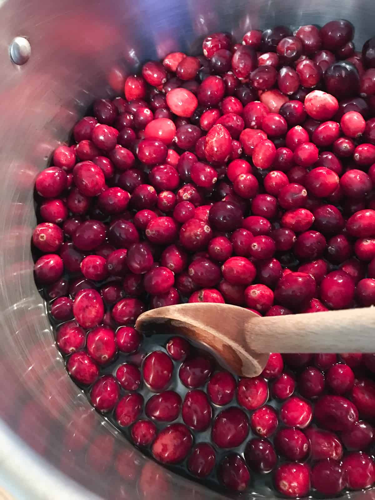 Raw cranberries in a pot with water.