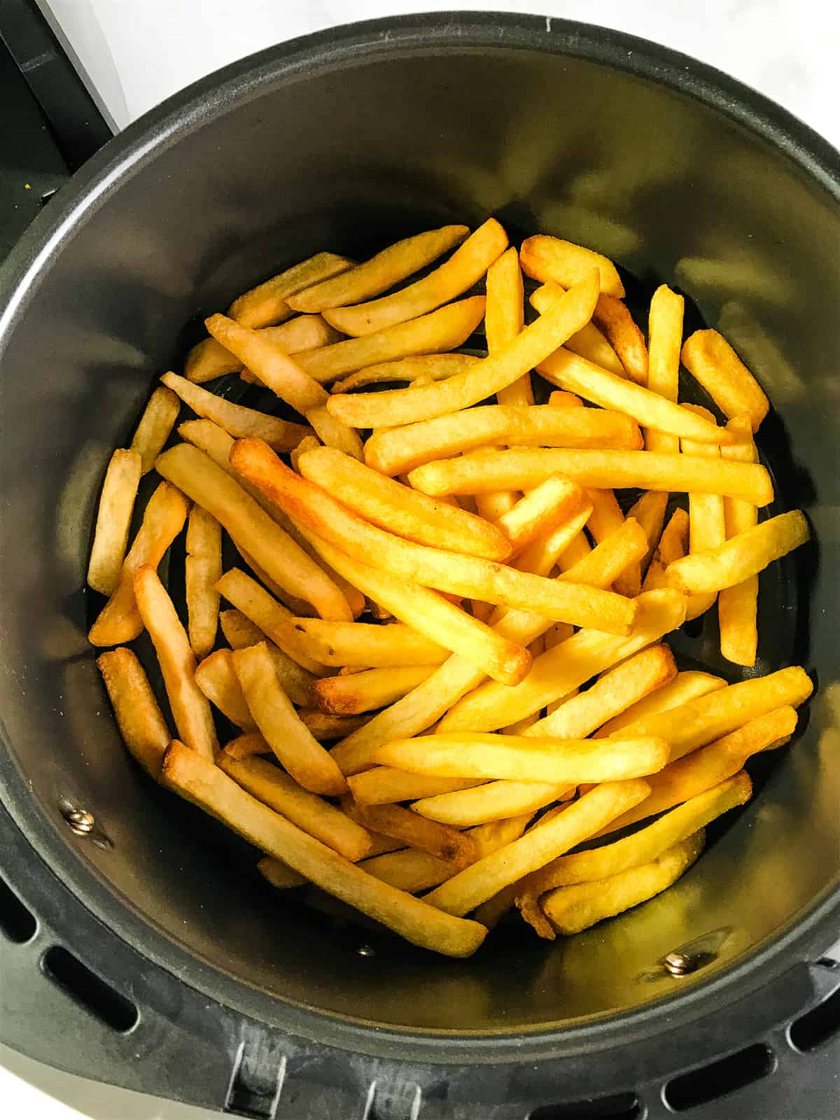 French fries in air fryer basket.