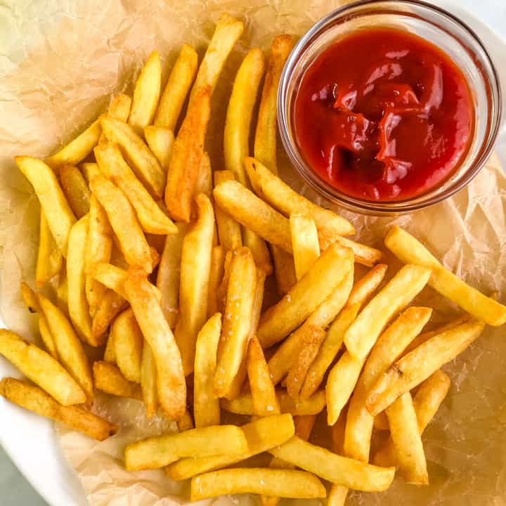 Air fryer cooked French fries on a platter with a small bowl of ketchup.