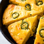 Baked cheddar jalapeno cornbread sliced in a skillet.