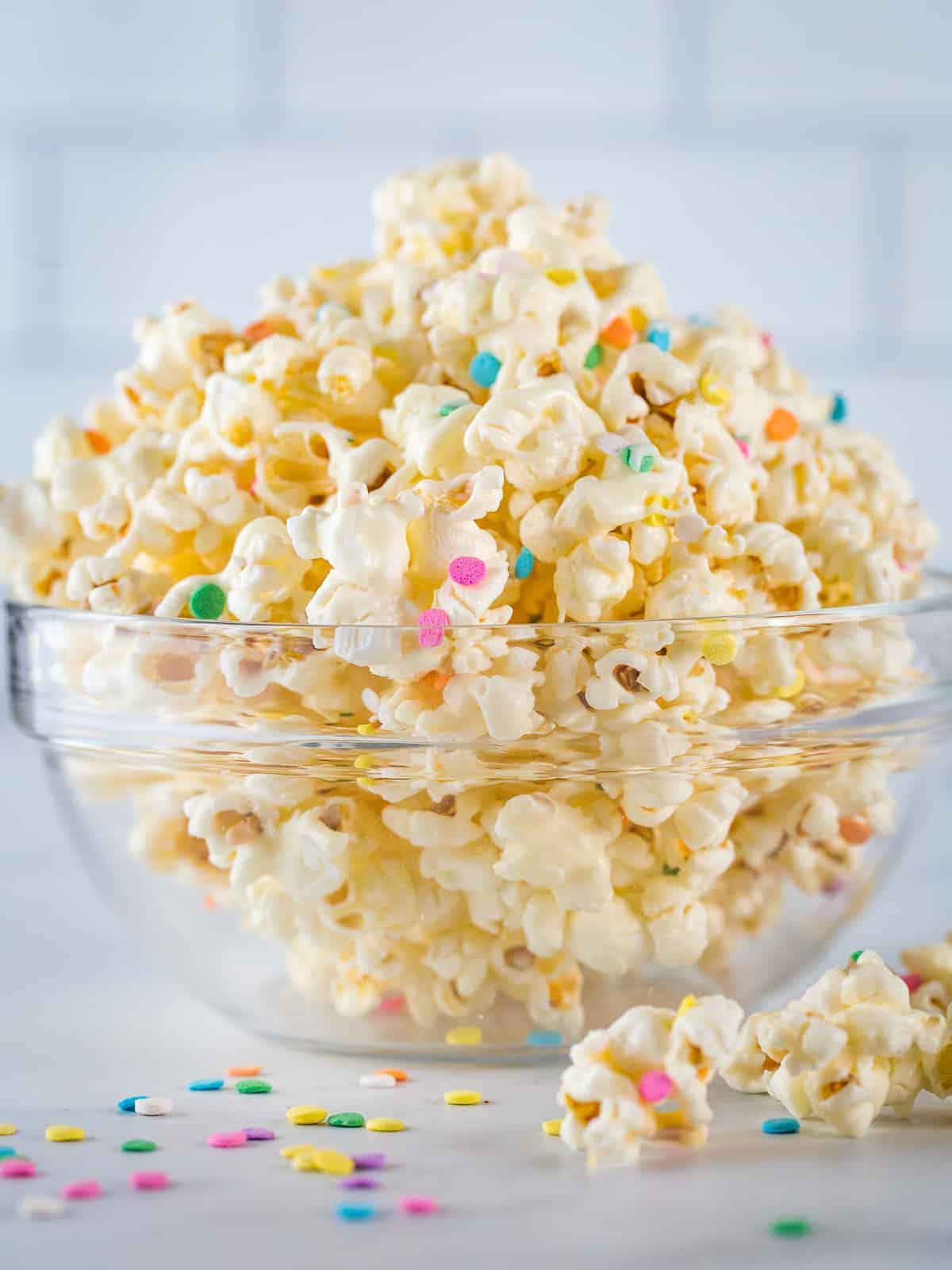 White chocolate popcorn with colorful sprinkles in a glass bowl.