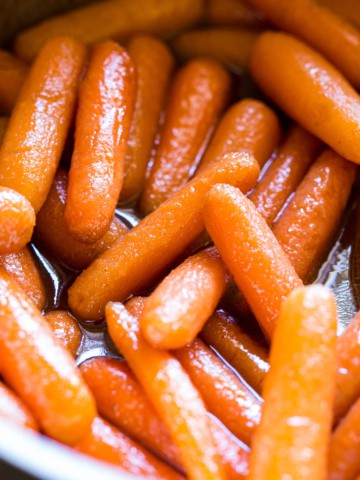 Cooked baby carrots in a brown sugar sauce.
