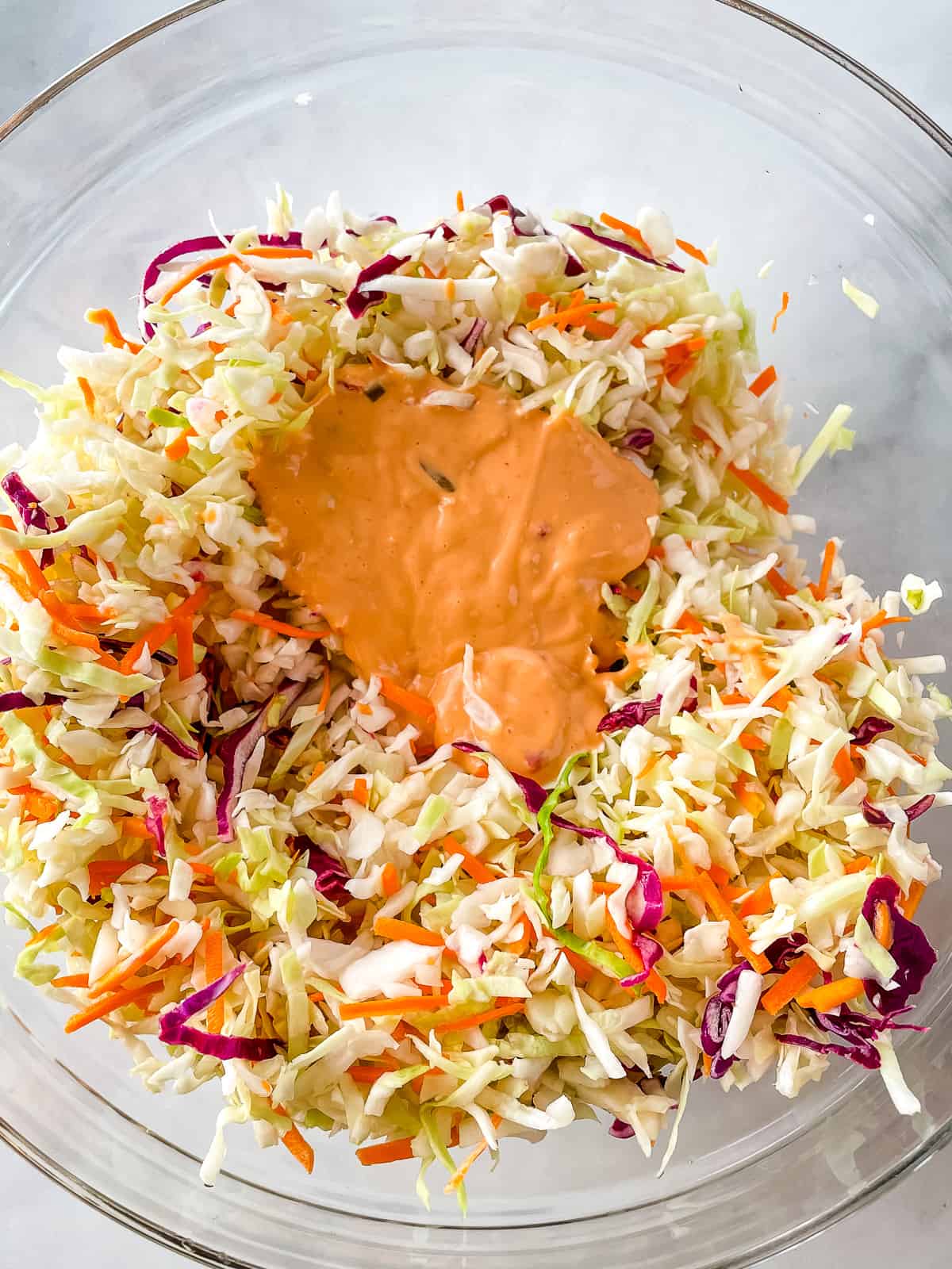 Coleslaw mix in bowl with Thousand Island dressing on it.