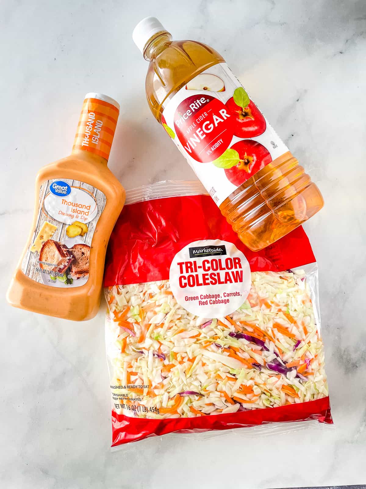 Ingredients for easy coleslaw. Bottle of dressing. Bottle of cider. Bag of coleslaw mix.