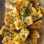 Sliced garlic bread on pan. Topped with fresh chopped parsley.