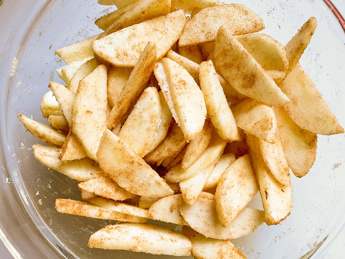 Sliced apples coated with flour, sugar, and cinnamon.