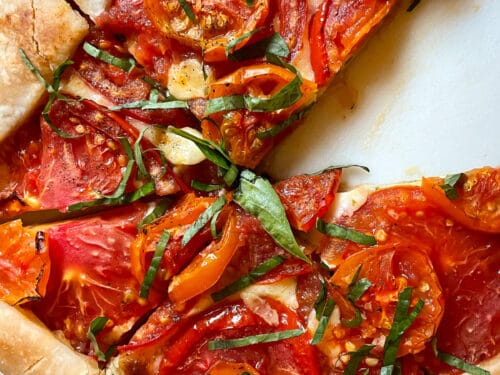 Premium Photo  Homemade galette or savory pie with red and yellow tomatoes  and basil on old newspaper or parchment paper. top view.