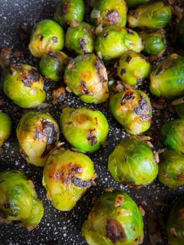 Frozen Brussels sprouts cooked with onions in a pan.