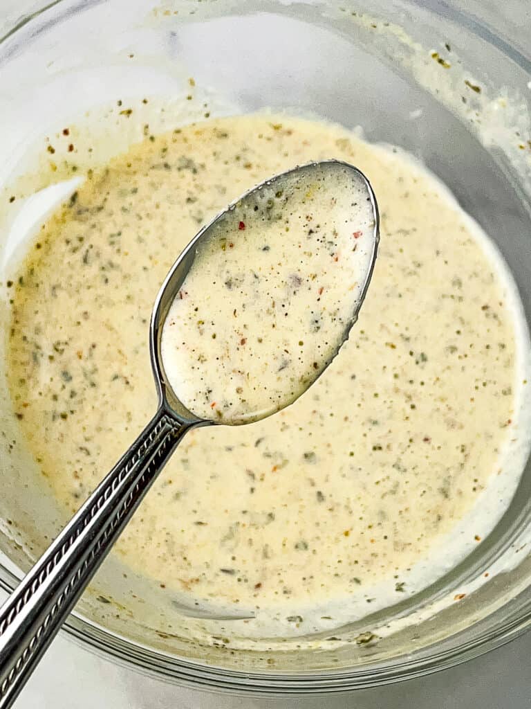 Creamy Italian dressing on a spoon over a bowl.