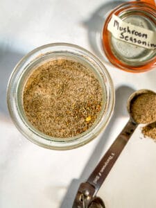 Homemade mushroom seasoning in jar. Teaspoon and lid sit off to the right side.