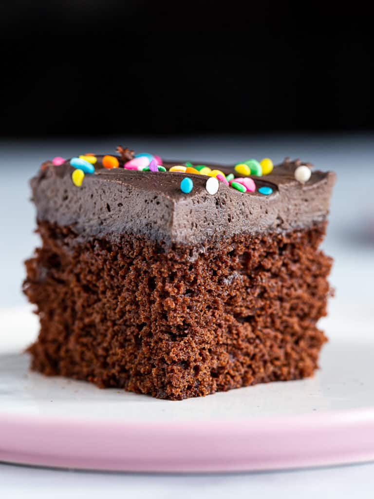 Slice of chocolate cake with chocolate frosting on a plate.