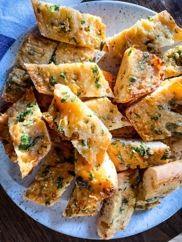 Roasted garlic bread slices on a plate.